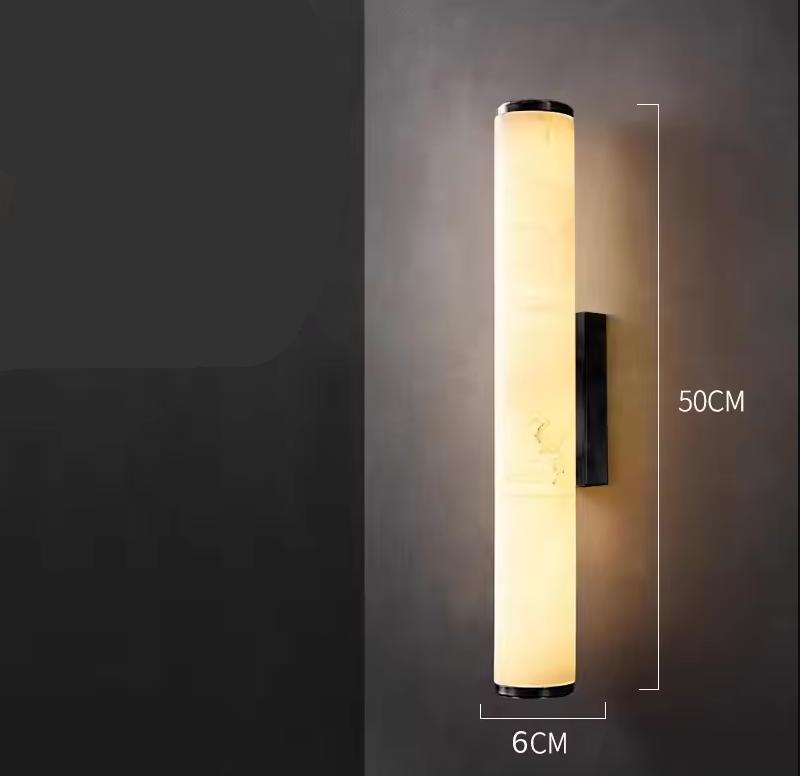 Brandende cilindrische marmeren wandlamp tegen een donkere muur, met maatlijnen die een hoogte van 50 cm en een breedte van 6 cm tonen. 21