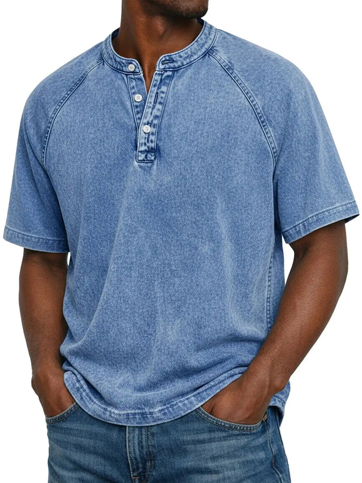 Man draagt het gewassen Henley-shirt met korte raglanmouwen in lichtblauw, gecombineerd met een spijkerbroek. 2