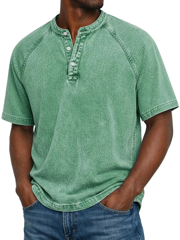 Man draagt het gewassen Henley-shirt met korte raglanmouwen in lichtgroen, gecombineerd met een blauwe spijkerbroek. 6