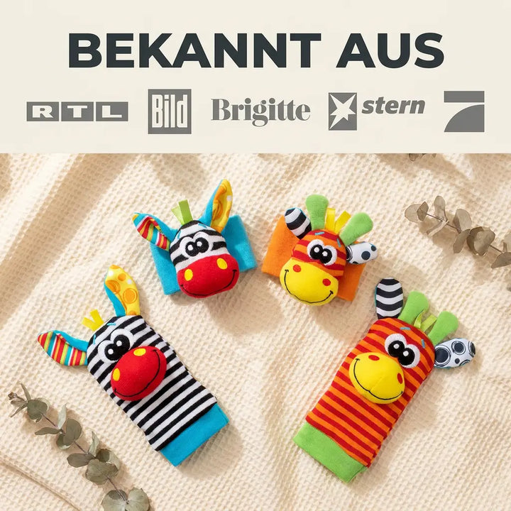 Vier rammelaars en sokjes met zebra- en giraffengezichtjes op een gebreide beige deken, tussen takjes eucalyptus. 7