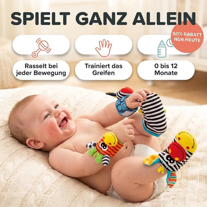 Lachende baby ligt op een gebreide deken en speelt met een gestreepte zebra-rammelaar om de pols en een rammelsok. 1