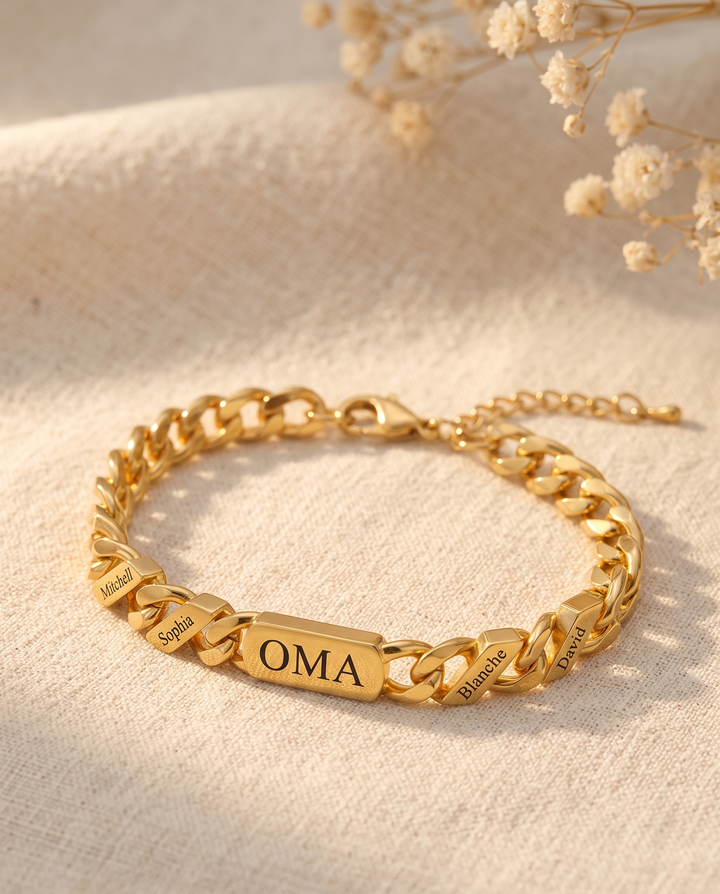 Gouden armband met gegraveerde namen op linnen stof, naast gedroogde witte bloemetjes, met karabijnslot en verlengkettinkje zichtbaar. 4