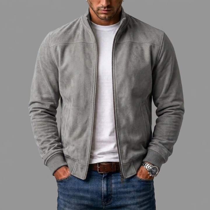 Grijze suèdelook jack, open gedragen over een wit T-shirt en jeans, met geribde zoom en handen in de zakken. 7