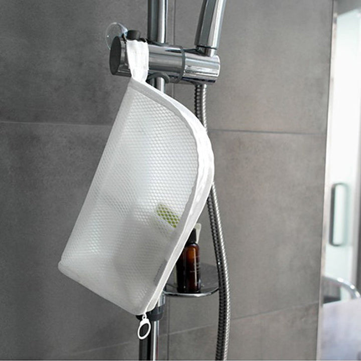 Witte mesh toilettas hangt met het lusje aan de douchestang in een grijs betegelde douche. 4