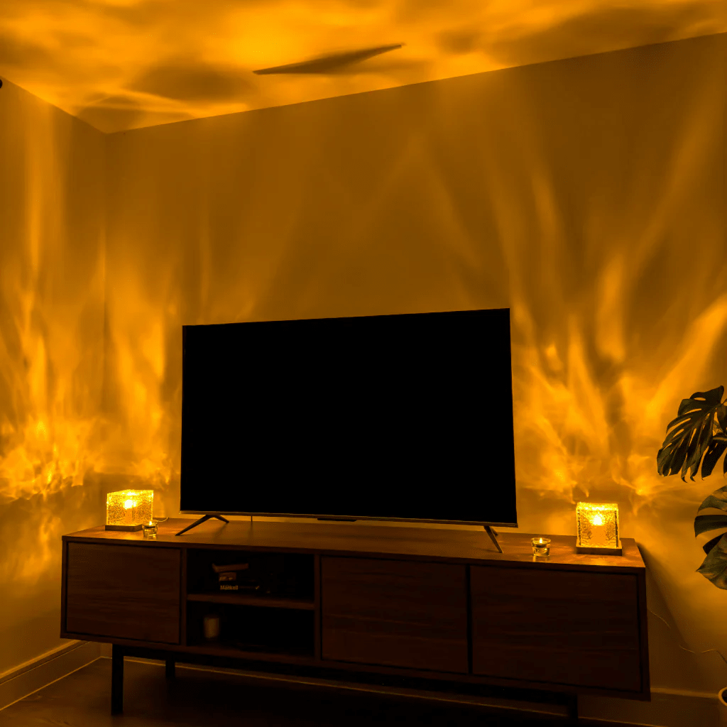 Twee kubuslampen op een tv-meubel in de woonkamer werpen warm geel golvend licht over de wanden en het plafond. 4