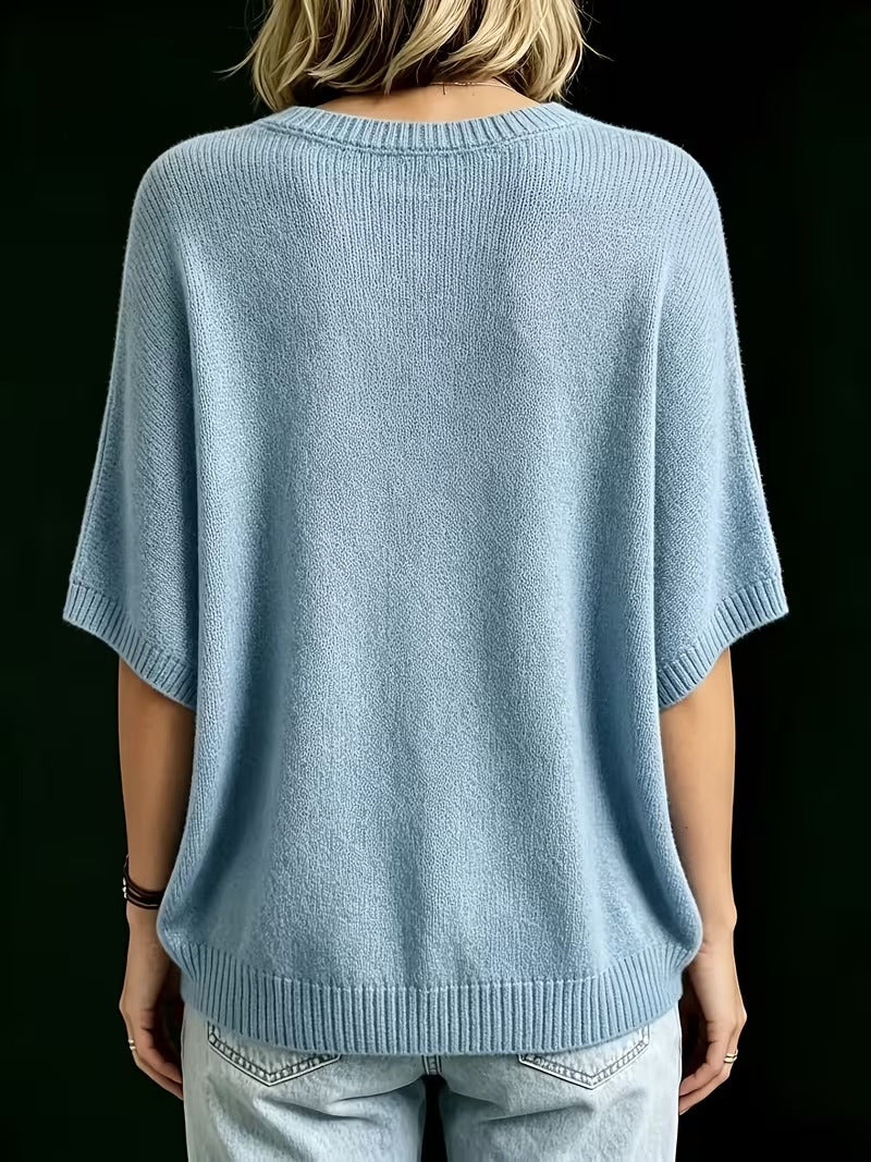 Achterkant van de lichtblauwe gebreide top met ronde hals, korte vleermuismouwen en geribbelde zoom, gedragen met jeans. 14