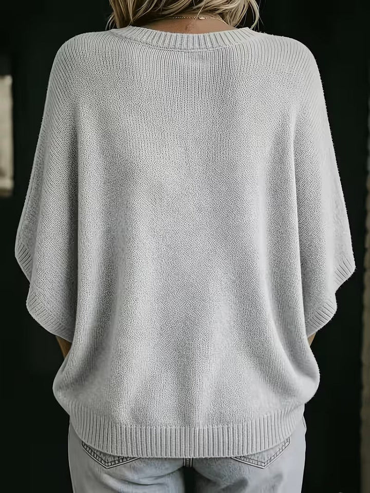 Achterkant van de lichtgrijze gebreide top met ronde hals, ruime vleermuismouwen en geribbelde zoom, gedragen met jeans. 3