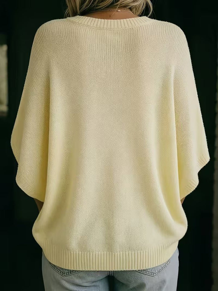 Achterkant van de lichtgele gebreide top met ronde hals en wijde vleermuismouwen, gedragen met lichte jeans. 6