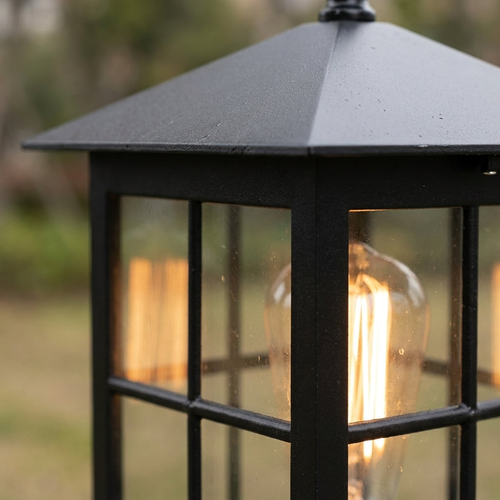 Close-up van het schuine zwarte dak en de raamverdeling van de lamp, met een gloeiende filamentlamp erachter. 6