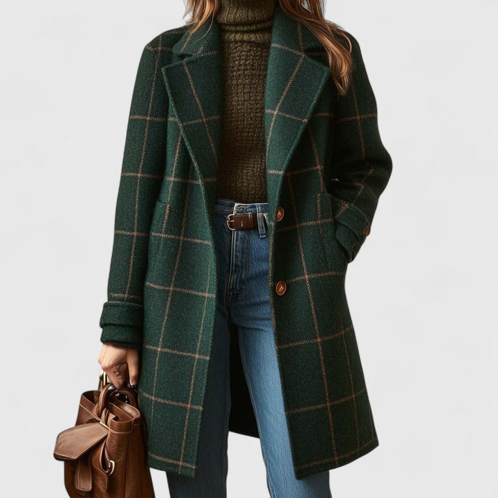 Model draagt de groene geruite jas open over een olijfgroene col en spijkerbroek, met een bruine leren tas in de hand. 1