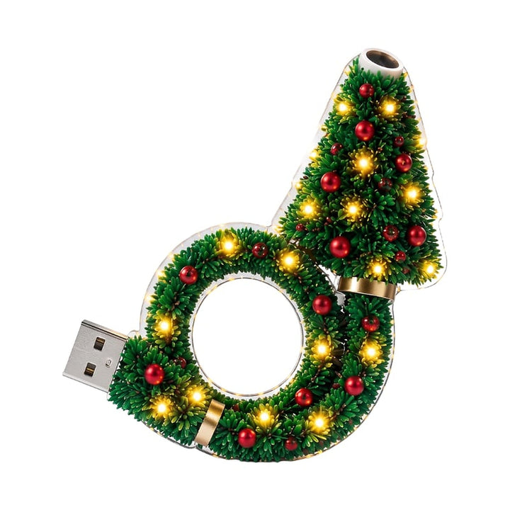 Projectorlamp met groene dennentakken, rode kerstballen en warme ledlampjes op een witte achtergrond, met USB-stekker links en lens bovenaan. 1
