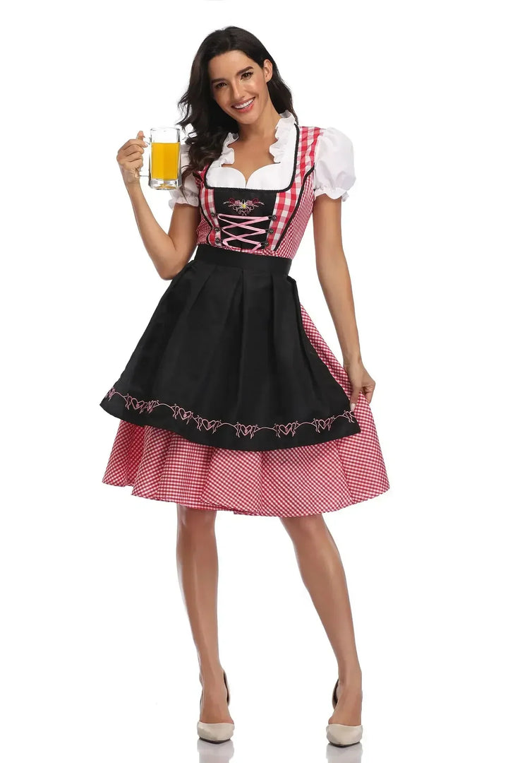 Model in rood geruite dirndl met zwarte schort met roze borduursel, houdt een bierglas vast en pakt de rok vast. 9