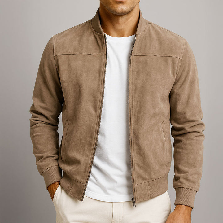 Model draagt de jack in taupe-beige, open ritssluiting over een wit T-shirt, met een hand in de zak van een crème broek. 1