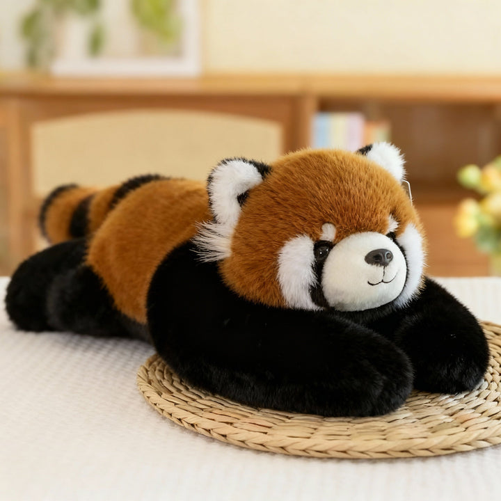 Rode panda-knuffel met roodbruine vacht, zwarte armen en gestreepte staart ligt op een rieten onderzetter. 13