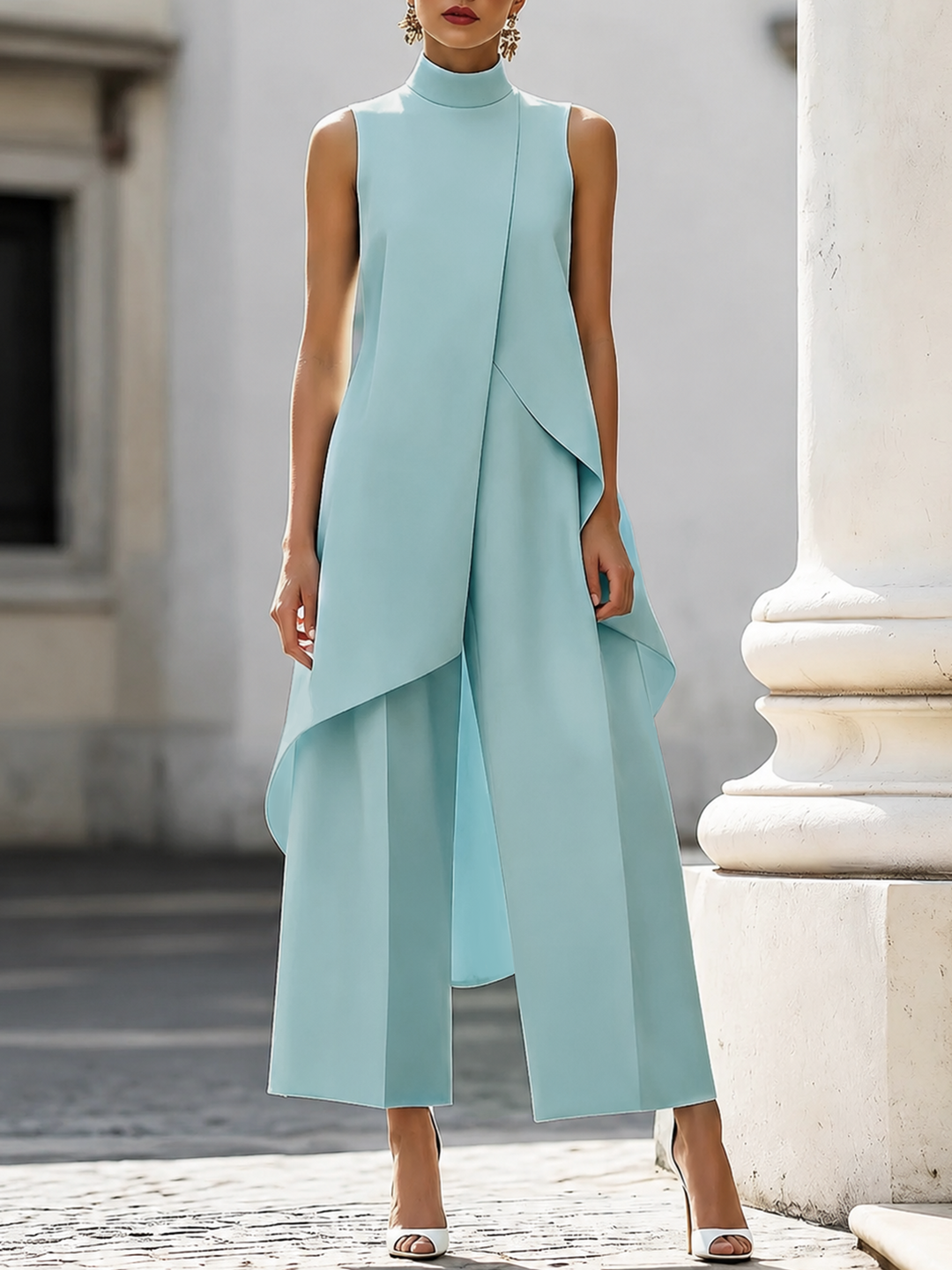 Lichtblauwe set met opstaande kraag, asymmetrische top en wijde broek, gedragen door een model bij een zuil. 4