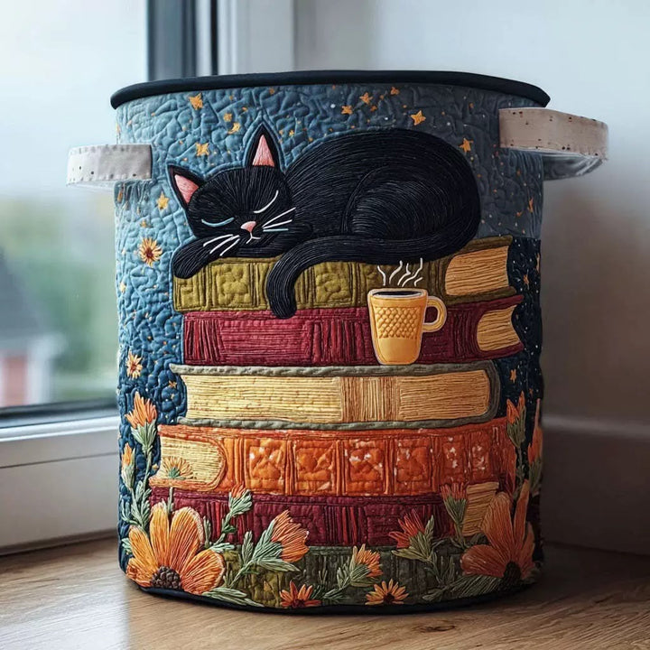 Ronde gewatteerde mand met crèmekleurige handgrepen en een geborduurde zwarte kat die slaapt op een stapel boeken naast een kopje koffie, bij een raam. 1