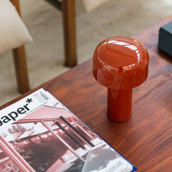 Rode glanzende tafellamp op een houten salontafel naast een tijdschrift, gezien van boven 14