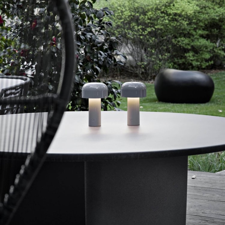 Twee grijze tafellampen met warm licht op een ronde buitentafel in de tuin 23