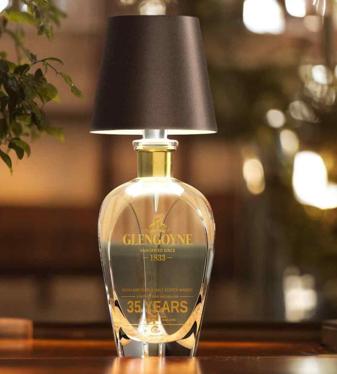 Donkerbruine lampenkap op een kristallen karaf met gouden hals, voor een warm uitgelichte, wazige achtergrond. 5
