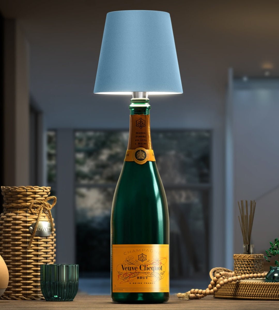 Lichtblauwe lampenkap op een donkergroene champagnefles, omringd door rieten manden en decoratie op een houten tafel. 6