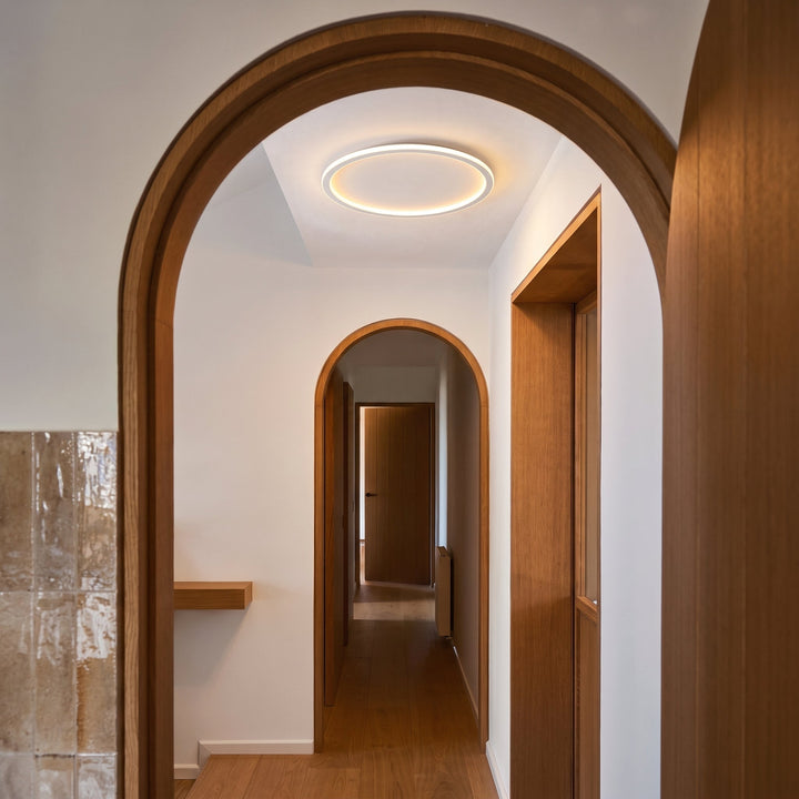 Ringvormige plafondlamp verlicht een hal met houten boogdeuren, eikenhouten vloer en een glanzende tegelwand. 4