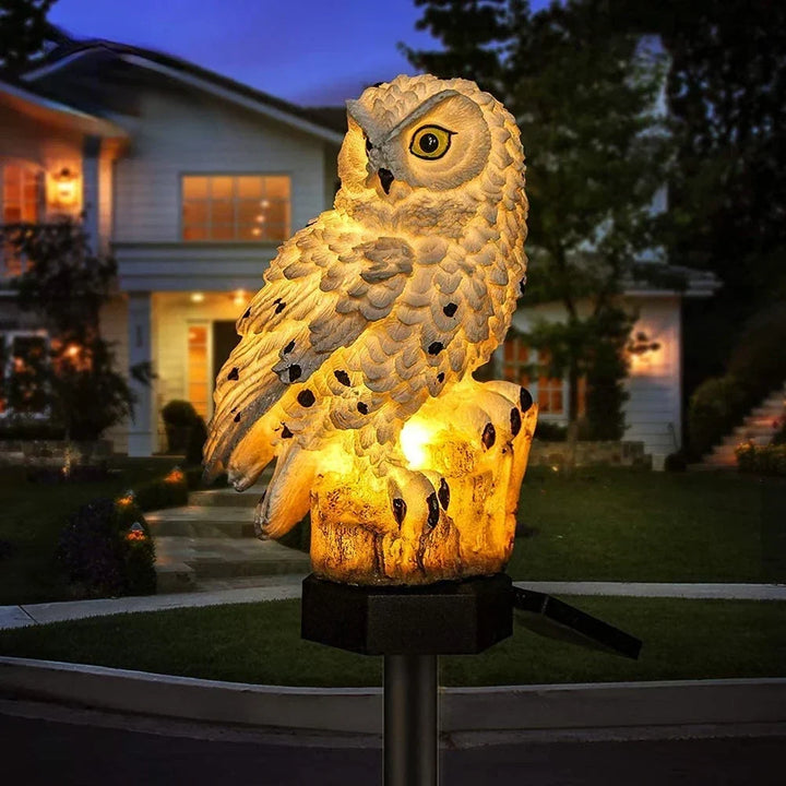 Lichte uilenlamp met zwarte stippen op een boomstronk, warm verlicht in de schemering voor een huis. 2
