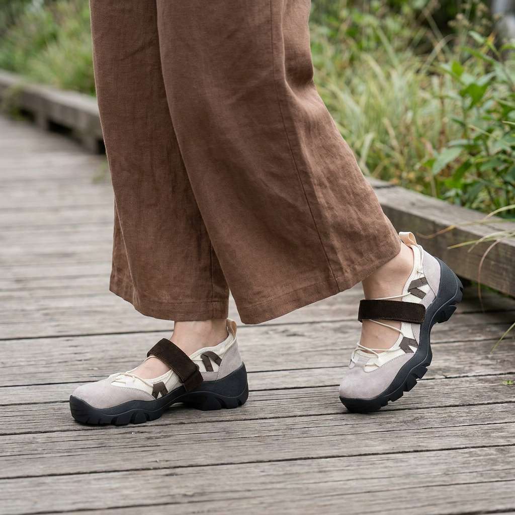 Taupe instappers met bruine klittenbandband, gedragen met een bruine linnen broek met wijde pijpen op een houten pad. 11