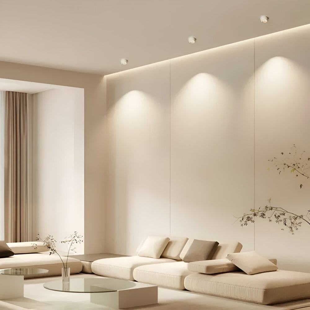Drie witte inbouwspots in het plafond van een lichte woonkamer, die de wand verlichten 2