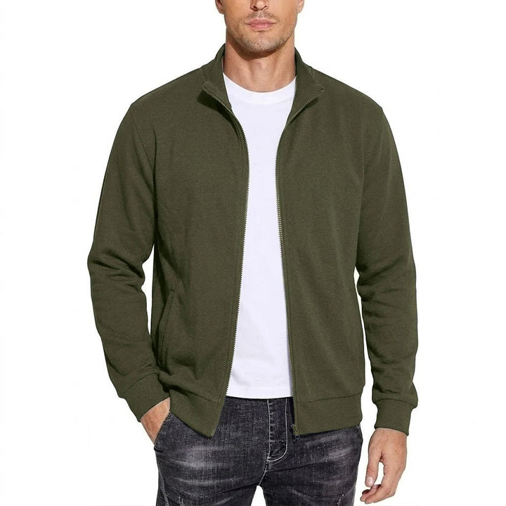 Model draagt de sweatjack in legergroen, open ritssluiting over een wit T-shirt, een hand in de zak. 6