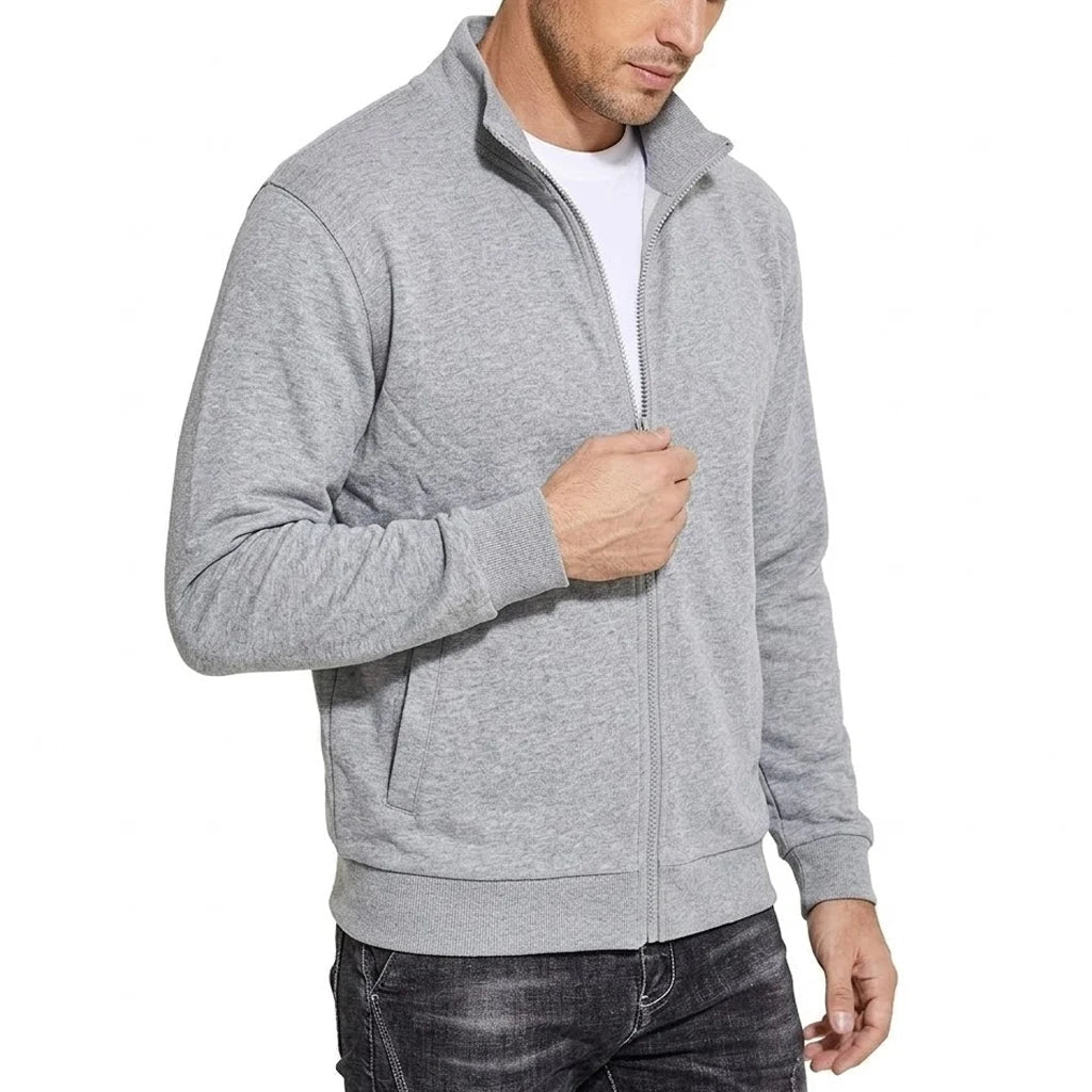 Schuin van voren: model in lichtgrijze sweatjack met opstaande kraag, hand bij de ritssluiting, ribboorden en zijzak zichtbaar. 2