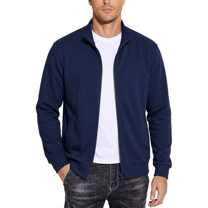 Model draagt de sweatjack in donkerblauw, open ritssluiting over een wit T-shirt, een hand in de zak. 3