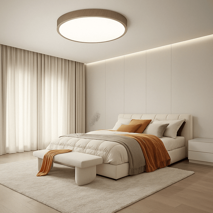 Ronde plafondlamp met houtlook rand boven een bed met crèmekleurig beddengoed en oranje plaid in een rustige slaapkamer. 12