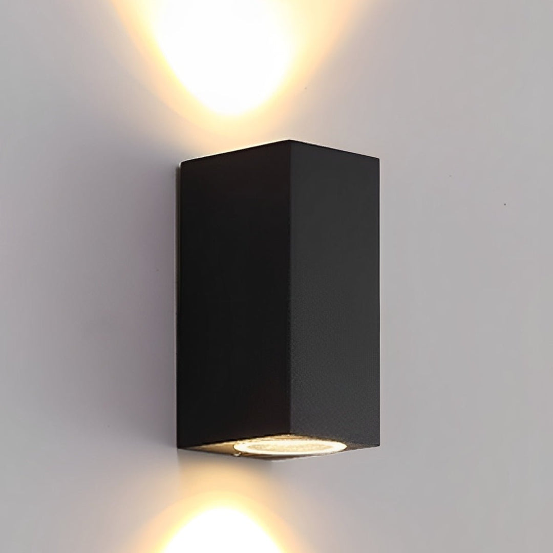 Zwarte langwerpige wandlamp die warm licht tegelijk omhoog en omlaag over een lichte muur werpt 3