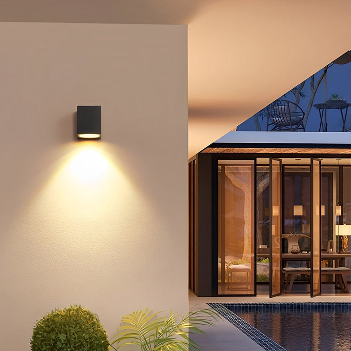 Zwarte wandlamp met neerwaarts licht naast een terras met glazen pui en zwembad 8
