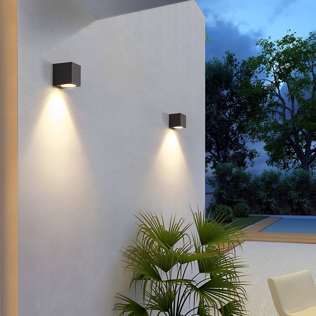 Twee zwarte kubuslampen met neerwaartse lichtkegels op een witte buitenmuur bij een zwembad 5