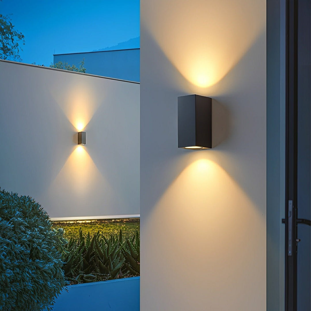 Twee zwarte dubbele wandlampen op witte muren, met licht omhoog en omlaag, naast een tuin 7