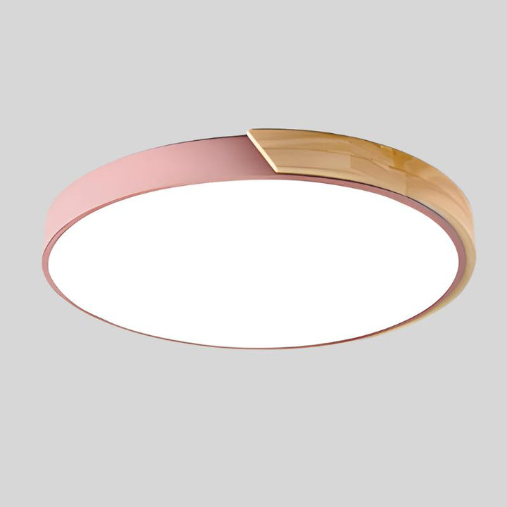 Roze ronde plafondlamp met houten accent aan de rand, vrijstaand getoond op een lichtgrijze achtergrond. 16