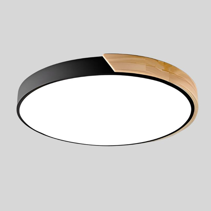Zwarte ronde plafondlamp met houten accent aan de rand, vrijstaand getoond op een lichtgrijze achtergrond. 17