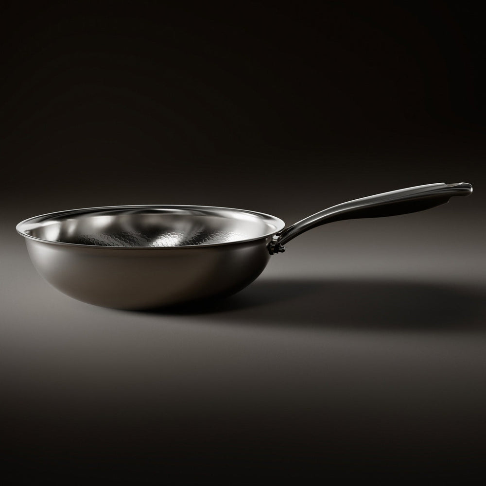 Zijaanzicht van de wokpan met gladde, gebogen buitenwand, platte bodem en lange metalen steel op een donkere ondergrond. 2
