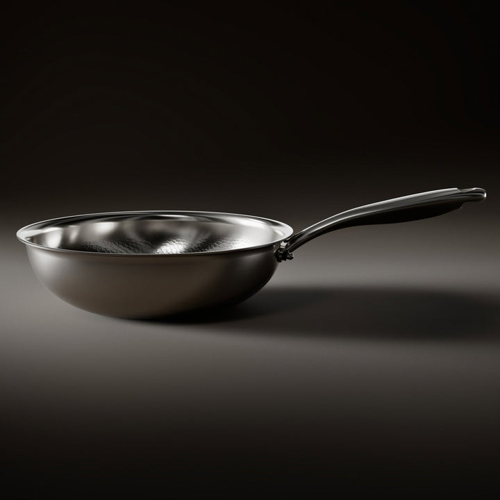 Zijaanzicht van de wokpan met gladde, gebogen buitenwand, platte bodem en lange metalen steel op een donkere ondergrond. 2