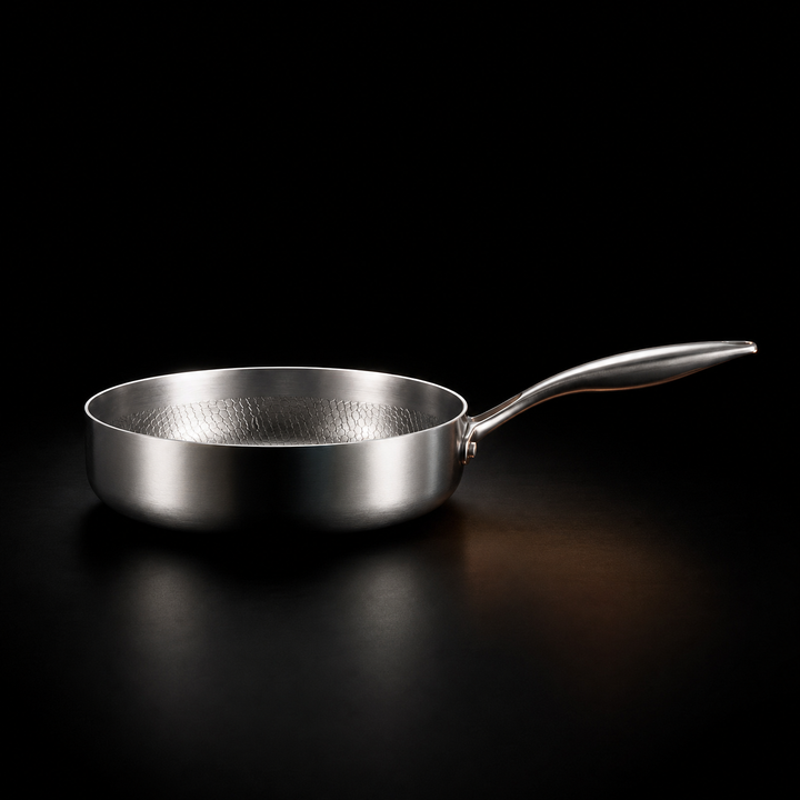 Zijaanzicht van de lage pan met hoge rand en gebogen steel op een zwarte ondergrond 2