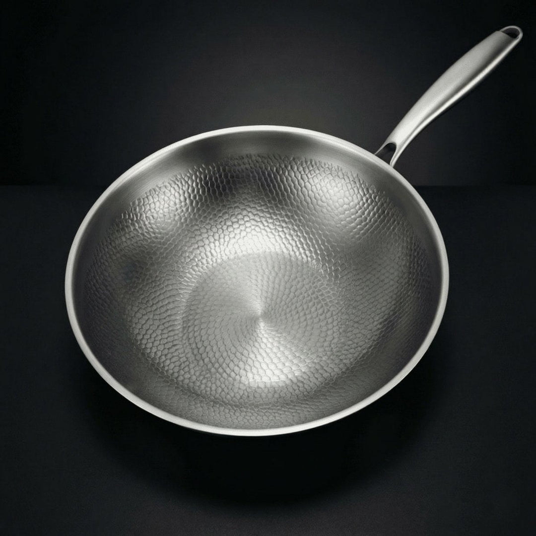 Bovenaanzicht van de lege wok met het gehamerde, schubbenachtige oppervlak aan de binnenkant en de metalen steel. 2
