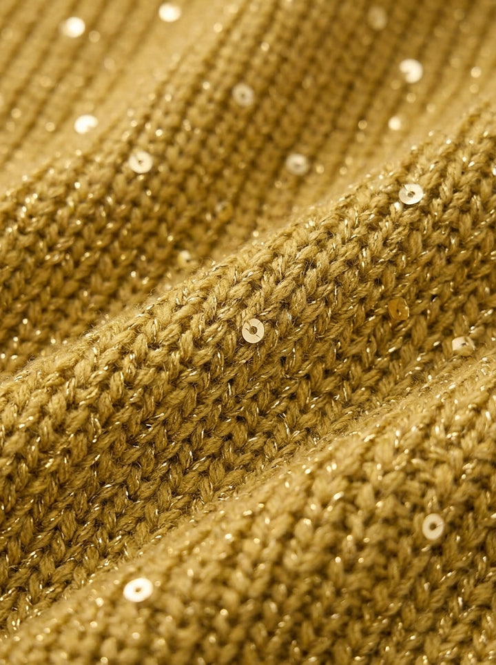 Close-up van het goudkleurige breisel met kleine glinsterende pailletten en metaaldraad, waarop de ribstructuur goed zichtbaar is. 13