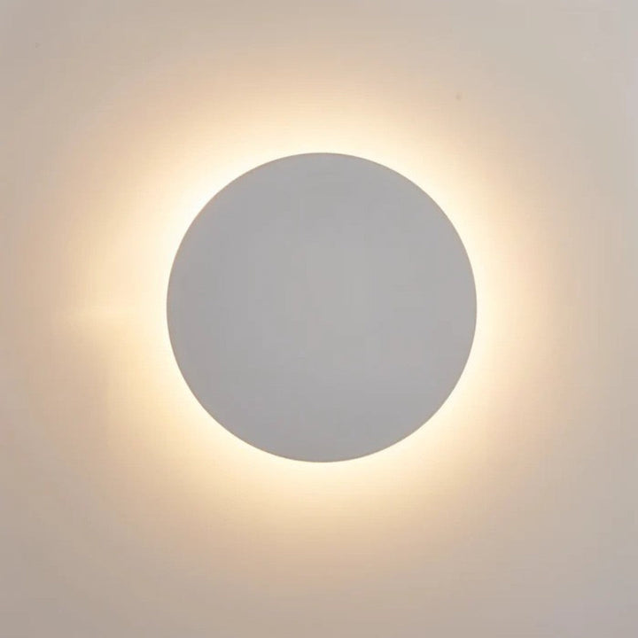 Close-up van de witte uitvoering: lichte ronde schijf met zachte warmwitte gloed op de muur 3