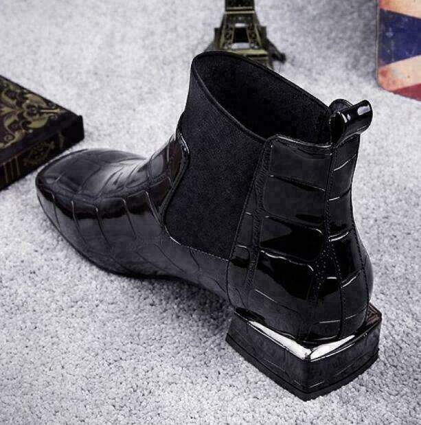 Zwarte enkellaars van achteren en opzij, met nadruk op het treklusje, de blokhak en het zilverkleurige randje op de hak. 3