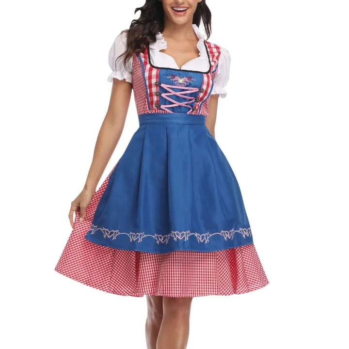 Model draagt de dirndl met heldere blauwe schort over een rood geruite rok, met roze veters en pofmouwen. 3