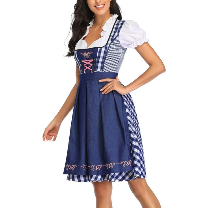 Close-up van het model in de blauw-wit geruite dirndl met donkerblauwe schort, hand op de heup, roze veters zichtbaar. 6