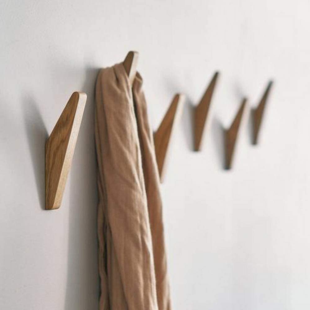 Rij houten haken aan een witte muur, waarvan een haak een beige sjaal draagt. 2
