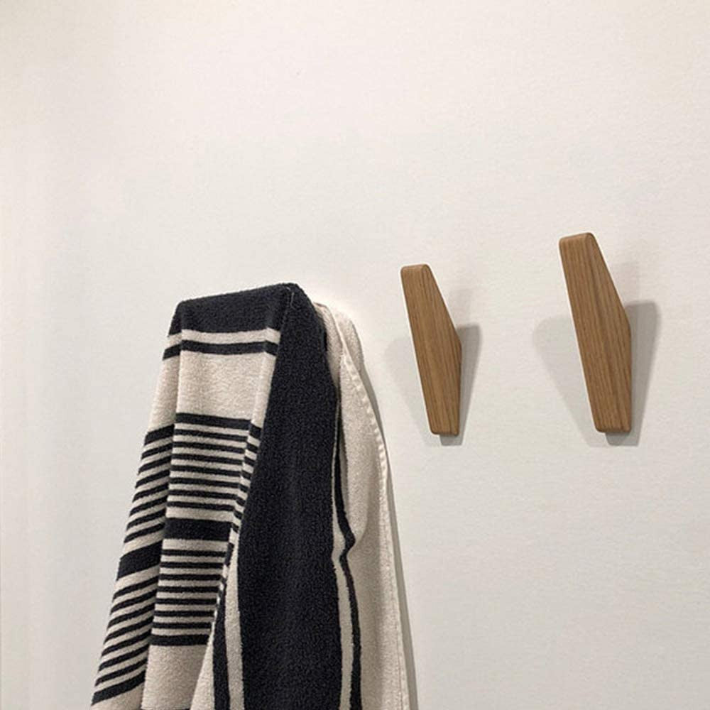 Twee houten wandhaken aan een witte muur naast een zwart-wit gestreepte handdoek die aan een haak hangt. 4