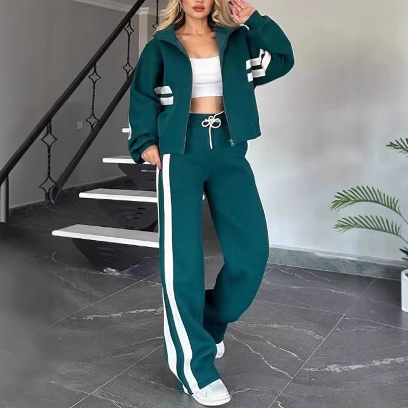 Model in de groene set met witte strepen, jack open over een witte top en broek met trekkoord. 5
